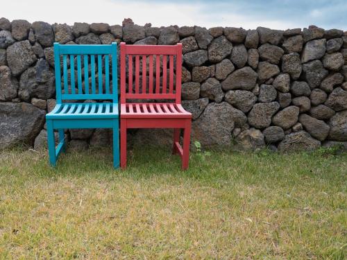 two colorful chairs sitting next to a stone wall at Boutique Pool Villa NAMIB in Jeju