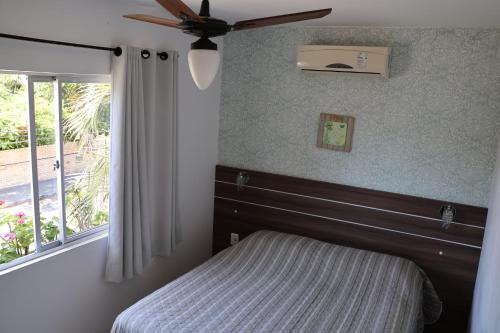 1 dormitorio con 1 cama, ventilador de techo y ventana en Floramar, en Florianópolis