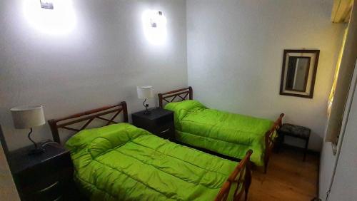 a bedroom with two beds with green sheets at Alquiler temporario 3 amb Parque Luro Mar del Plata in Mar del Plata