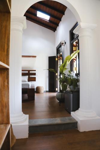 a hallway with white columns and a bedroom at Roots Retreat in Unawatuna