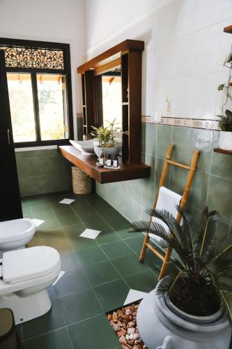 a bathroom with two toilets and a green floor at Roots Retreat in Unawatuna