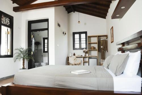 a bedroom with a large white bed with a book on it at Roots Retreat in Unawatuna