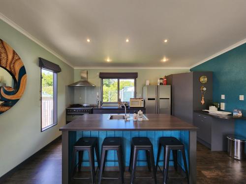 a kitchen with a large island with bar stools at The perfect Hahei bach - Dulop in Hahei