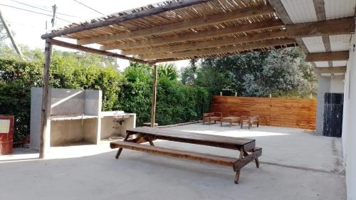 un patio con pérgola de madera y un banco en Complejo Martin’s en Del Viso