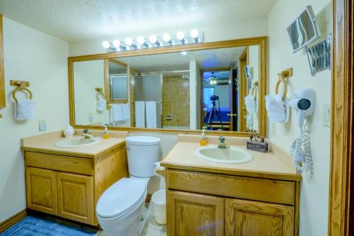 een badkamer met een toilet, 2 wastafels en een spiegel bij Tree House in Brian Head