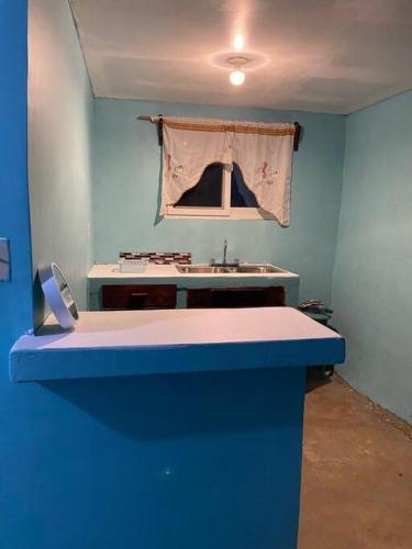 ein Badezimmer mit einem Waschbecken und einer blauen Wand in der Unterkunft Low Key Apartment in Punta Blanca
