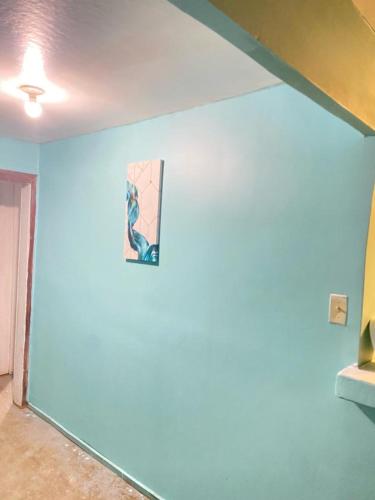 ein Zimmer mit einer blauen Wand mit einem Gemälde darauf in der Unterkunft Low Key Apartment in Punta Blanca