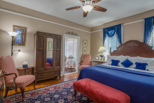 a bedroom with a bed and chairs and a ceiling fan at Victorian House Bed and Breakfast in Saint Augustine