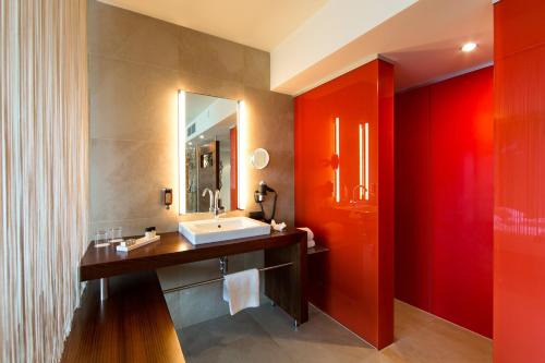 a bathroom with a sink and a red wall at Das Seepark Wörthersee Resort in Klagenfurt