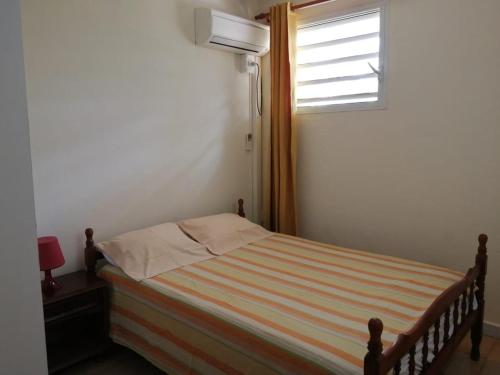 uma pequena cama num quarto com uma janela em Bas de villa Aka Cecette em Petit-Bourg