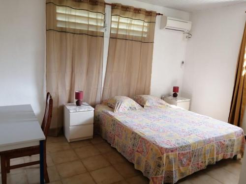 a bedroom with a bed and a table and a window at Bas de villa Aka Cecette in Petit-Bourg