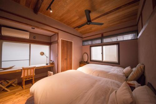 a bedroom with a bed and a desk and a window at はなれ奏HanareSou-天然温泉付き貸別荘-1棟貸し in Kirishima