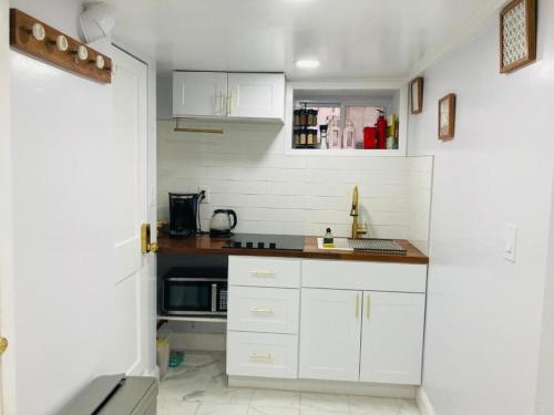 een keuken met witte kasten en een magnetron bij The Green House w/ private ent in Brooklyn