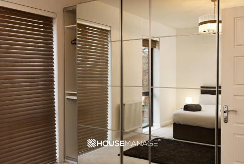 Un vestidor de cristal con una cama en un dormitorio en Modern Beautiful 5 bed -Sleeps 13 - Jacuzzi and Free Parking en Coulsdon