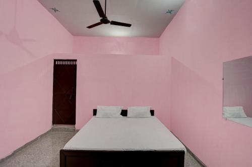 OYO Hotel star palace في نويدا: غرفة وردية مع سرير ومروحة سقف