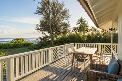 - une terrasse couverte avec une table et des chaises et l'océan dans l'établissement Hale Kalani home, à Haena