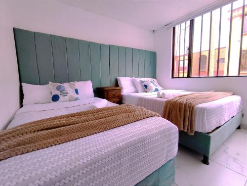 1 dormitorio con 2 camas y 2 ventanas en Casa Cielo en Paipa Centro, en Paipa