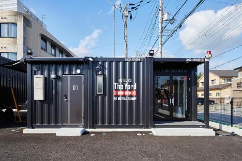 un edificio negro con una puerta en un estacionamiento en HOTEL R9 The Yard 長浜, en Nagahama