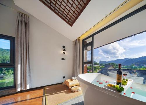 a bath tub in a room with a large window at Riverside Peak Lodge Zhangjiajie Wulingyuan National Park in Zhangjiajie