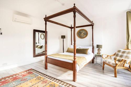 a bedroom with a four poster bed and a chair at Victorian Style Apartment w/ Four-Poster Bed in Camden Town in London