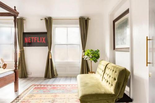 a living room with a green chair and a window at Victorian Style Apartment w/ Four-Poster Bed in Camden Town in London