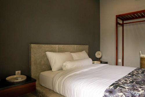 a bedroom with a large bed with white sheets at Uluwatu Stay's Standard Room #1 in Uluwatu