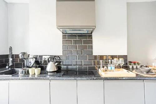 a kitchen with white cabinets and a counter top at Victorian Style Apartment w/ Four-Poster Bed in Camden Town in London