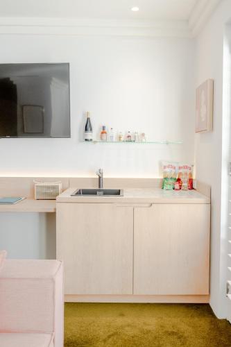 a kitchen with white cabinets and a sink at Hotel Ravesis in Sydney