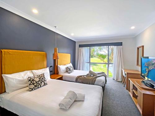 a hotel room with two beds and a television at Villa On The Green in Lovedale