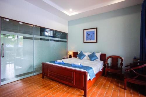 Brenta Phu Quoc Hotel في فو كووك: غرفة نوم مع سرير ودش زجاجي