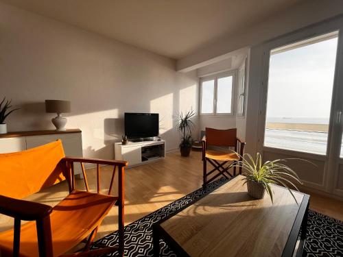 un salon avec une table, des chaises et une télévision dans l'établissement Studio spacieux face mer avec balcon et garage, proche plage et commerces aux Sables-d'Olonne - FR-1-197-561, à Les Sables-dʼOlonne