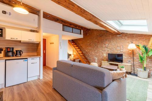 un salon avec un canapé et un mur de briques dans l'établissement Pretty haven of peace in Saint-Cyprien, à Toulouse