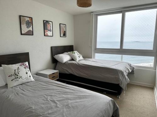 a bedroom with two beds and a large window at Primera línea, vista increíble in Papudo