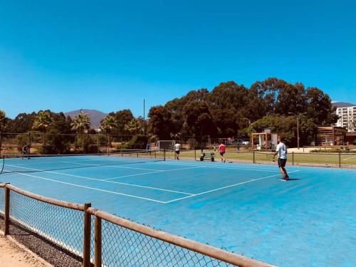 un groupe de personnes jouant au tennis sur un court de tennis dans l'établissement Primera línea, vista increíble, à Papudo