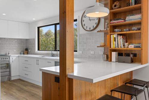 a kitchen with white counters and a clock on the wall at Shangri La - Wifi Included in Inverloch