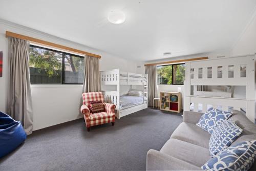 a bedroom with two bunk beds and a couch at SHANGRI-LA ON SURF PARADE - FREE WIFI! in Inverloch