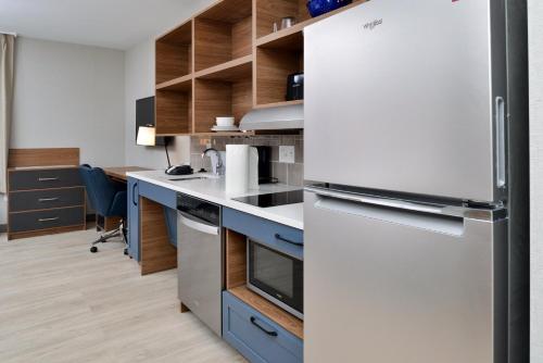 a kitchen with a white refrigerator and blue cabinets at Candlewood Suites - Joliet Southwest by IHG in Joliet