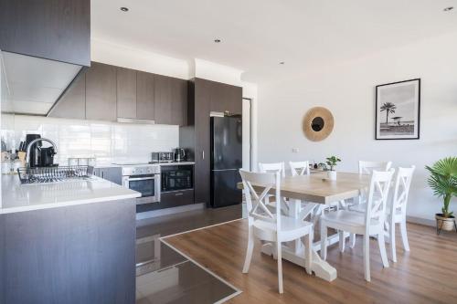 a kitchen with a wooden table and white chairs at Capel Sound Family Comforts on the Foreshore in Rosebud