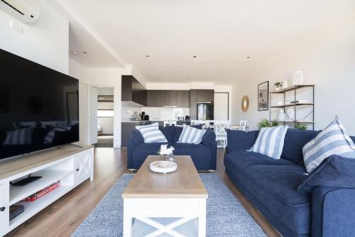 a living room with a blue couch and a tv at Capel Sound Family Comforts on the Foreshore in Rosebud