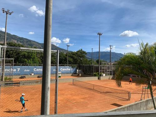 una persona sta giocando a tennis su un campo da tennis di Acogedor Apartaestudio Tricentenario Medellín a Medellín