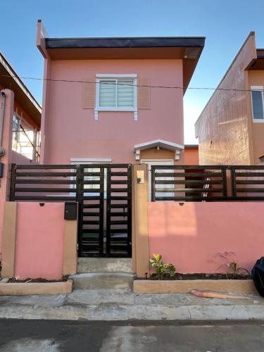 a pink house with a black gate at Cozy Staytion House at Camella Homes Vigan City in Bantay