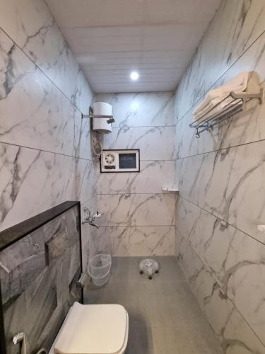 a bathroom with a toilet and a marble wall at Green Villa - Luxury Rooms at peaceful location -200 mtrs away from Bus Stand -500 mtrs from Udaipur Railway Station - Family Suites w Kitchen also available in Udaipur