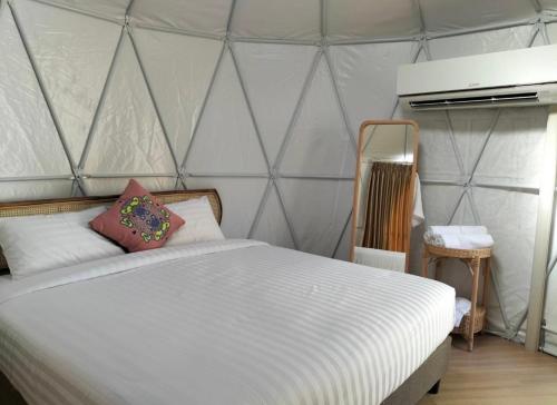 1 dormitorio con cama blanca y tienda de campaña en ภูเพียงพอ ณ เชียงราย, en Chiang Rai