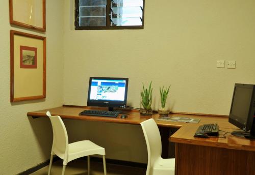 an office with a desk with a computer and two chairs at Cresta Sprayview Victoria Falls in Victoria Falls