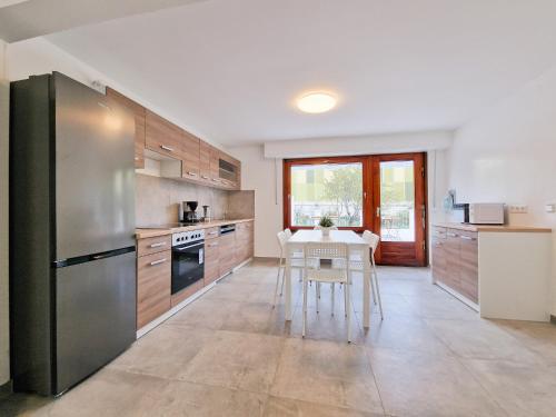 a kitchen with a table and a stainless steel refrigerator at RAJ Living - 6 Room House with Terrace and Parking - 25 Min Messe DUS & Airport DUS in Duisburg