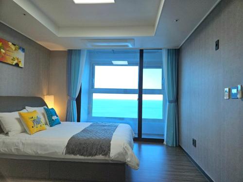 1 dormitorio con 1 cama y ventana grande en Eastern View Premium Residence, en Ulsan