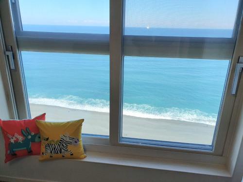 two pillows sitting on a window sill looking out at the ocean at Eastern View Premium Residence in Ulsan