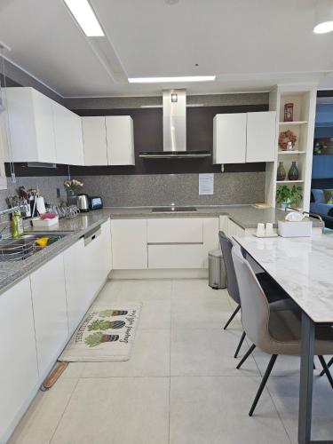 a kitchen with white cabinets and a table and chairs at 이스턴뷰 프리미엄 레지던스 100프로오션뷰 in Ulsan