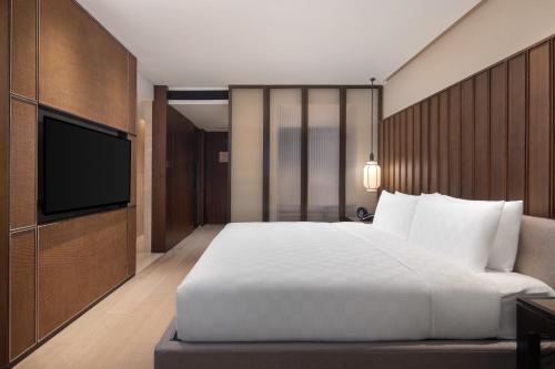 a bedroom with a large bed and a flat screen tv at HUALUXE Xi'an Tanghua by IHG in Xi'an