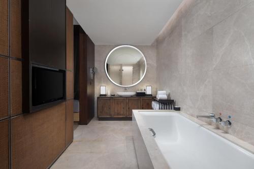 a bathroom with a tub and a large mirror at HUALUXE Xi'an Tanghua by IHG in Xi'an
